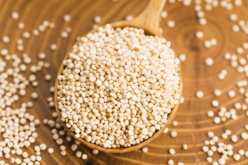 White quinoa seeds on a wooden background